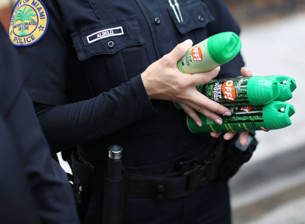 MIAMI, FL - AUGUST 02: Michelle Albelo, A City of Miami police officer, gives out cans of insect repellent to help people near the Miami Rescue Mission prevent mosquito bites that may infect them with the Zika virus on August 2, 2016 in Miami, Florida. A reported 14 individuals have been infected with the Zika virus by local mosquitoes. (Photo by Joe Raedle/Getty Images)