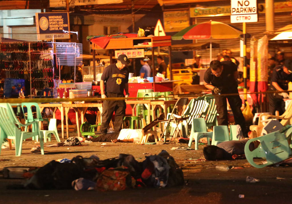 Philippine police officers look at dead victims after an explosion at a night market that has left about 10 people dead and wounded several others in southern Davao city, Philippines late Friday Sept. 2, 2016. Regional military commander Lt. Gen. Rey Leonardo Guerrero says it was not immediately clear what caused the explosion. (AP Photo/Manman Dejeto)