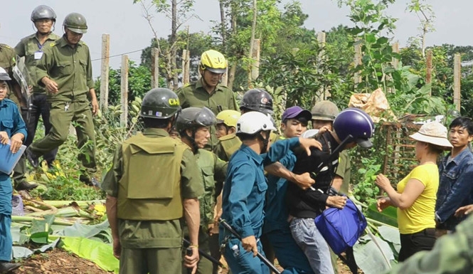 Nhiều công an và dân quân vây chặt ông Hải (áo đen) để giật các phương tiện làm việc. (Hình: Thanh Niên)