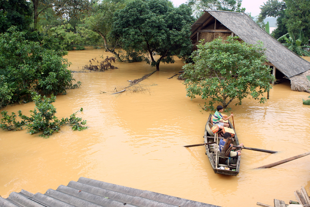This picture taken on October 16, 2016 shows villagers in a boat transporting boxes of instant noodles they received as relief aid past flooded homes in a village in Huong Khe district in the central province of Ha Tinh. Severe flooding in central Vietnam has killed at least 25 people and destroyed thousands of homes, officials said on October 17, as the country braced for further destruction with a typhoon barrelling closer. / AFP / Vietnam News Agency / STR (Photo credit should read STR/AFP/Getty Images)