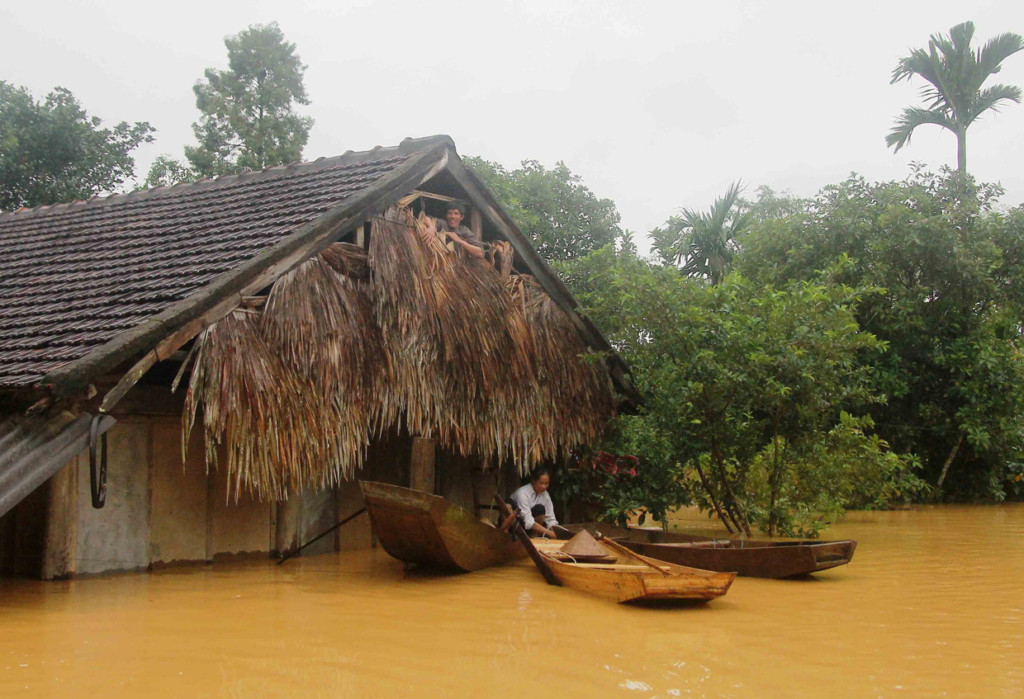 TOPSHOT - A Vietnamese villager sits on a boat next to his flooded home in Huong Khe district in the central province of Ha Tinh on October 15, 2016. At least 11 people have died with several more missing in heavy flooding in central Vietnam, state media said on October 15, 2016, with tens of thounsands of homes completely submerged by water. / AFP / VIETNAM NEWS AGENCY (Photo credit should read VIETNAM NEWS AGENCY/AFP/Getty Images)