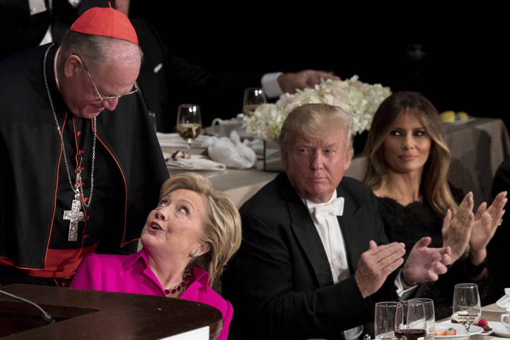 Republican presidential candidate Donald Trump, second from right, and his wife Melania Trump, right, watch as Democratic presidential candidate Hillary Clinton, second from left, is helped into her chair by Cardinal Timothy Dolan, Archbishop of New York, left, after speaking at the 71st annual Alfred E. Smith Memorial Foundation Dinner, a charity gala organized by the Archdiocese of New York, Thursday, Oct. 20, 2016, at the Waldorf Astoria hotel in New York. (AP Photo/Andrew Harnik)