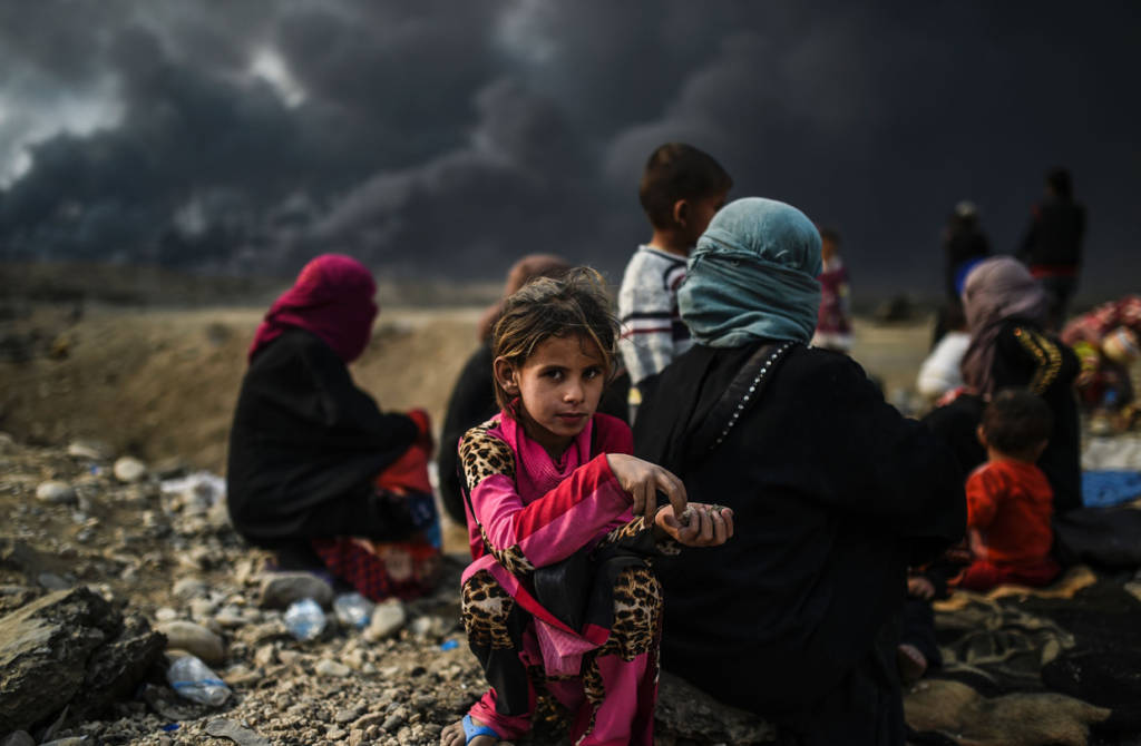 Iraqi families who were displaced by the ongoing operation by Iraqi forces against jihadists of the Islamic State group to retake the city of Mosul, are seen gathering in an area near Qayyarah on October 24, 2016. The UN refugee agency is preparing to receive 150,000 Iraqis fleeing fighting around the Islamic State group-held city of Mosul within the next few days, its chief said. / AFP / BULENT KILIC (Photo credit should read BULENT KILIC/AFP/Getty Images)