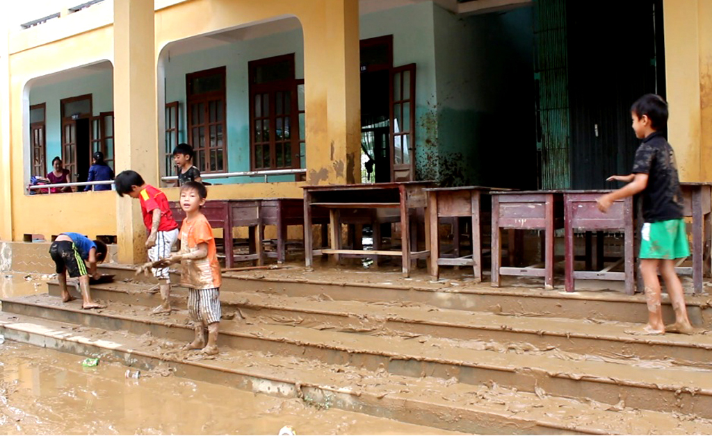 Các em nhỏ dọn dẹp trường học sau cơn lũ. (Hình: Liêu Thái/Người Việt)