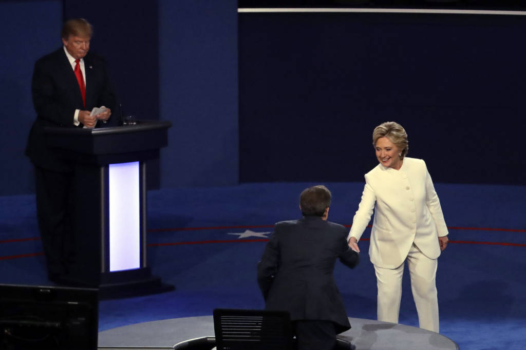 Bà Clinton bước tới bắt tay điều hợp viên Chris Wallace trong khi ông Trump vẫn còn đứng ở bục. (Hình: AP Photo/Julio Cortez)