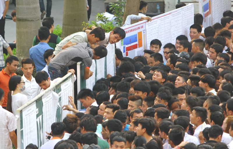 Nhiều người không kiên nhẫn chờ, trèo ngược rào để xem bảng danh sách, sơ đồ phòng thi. (Hình: VNExpress)
