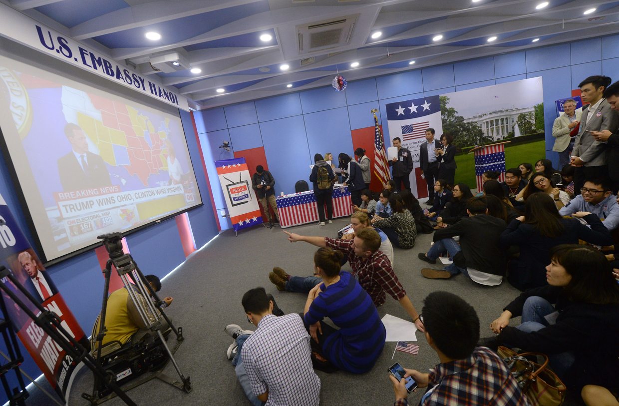 American and Vietnamese sit on the floor watching the results of the US presidential elections during an event at the US embassy in Hanoi on November 9, 2016. / AFP / HOANG DINH NAM (Photo credit should read HOANG DINH NAM/AFP/Getty Images)
