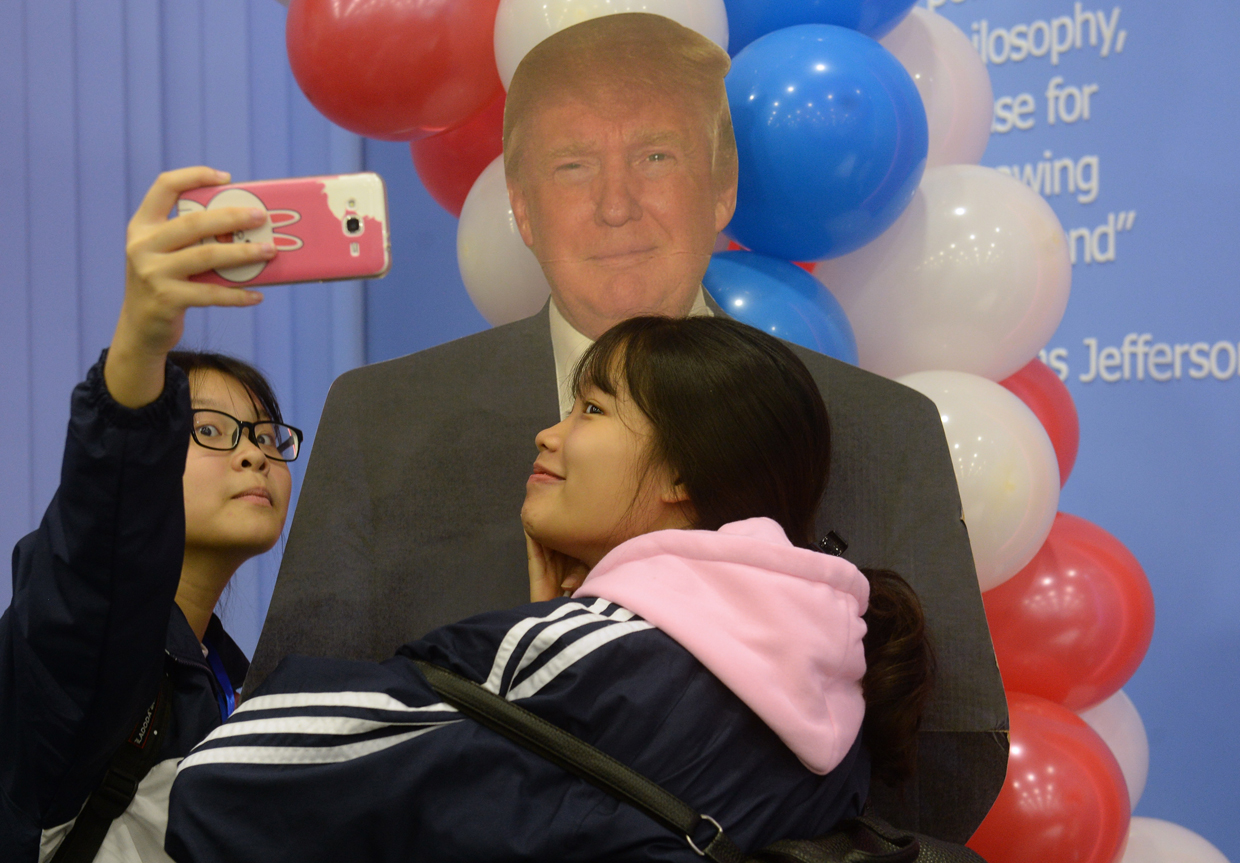 TOPSHOT - Two Vietnamese students take a selfie with a paper model of the US Republican presidential candidat during an election watch event at the US embassy in Hanoi on November 9, 2016. / AFP / HOANG DINH NAM (Photo credit should read HOANG DINH NAM/AFP/Getty Images)