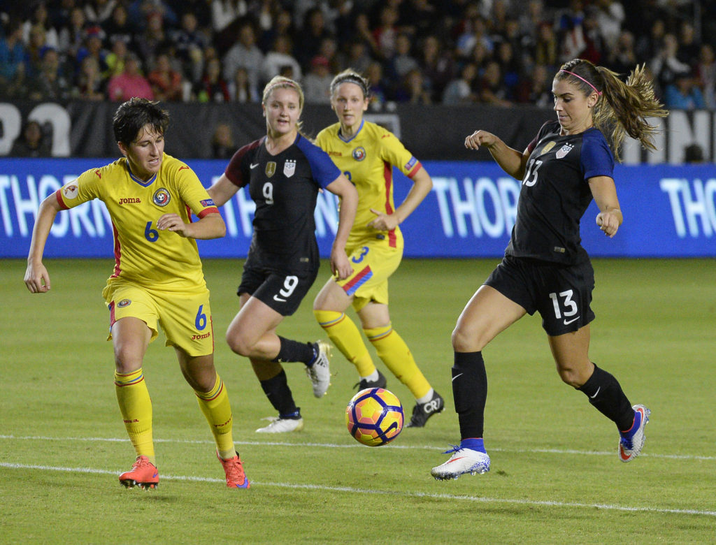 Alex Morgan số 13 của tuyển nữ Mỹ dẫn banh trước sự truy cản của các nữ cầu thủ Romania trong trận cầu giao hữu giữa hai đội tuyển nữ Hoa Kỳ và Romania diễn ra trên sân StubHub Center, Carson, California ngày 13 Tháng Mười Một, 2016. (Hình: Getty Images)