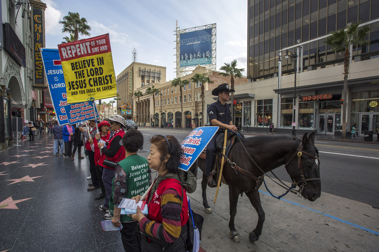 LOS ANGELES, CA - DECEMBER 06: A Los Angeles Police Department Mounted Platoon officer rides past a group of evangelizing Christians on Hollywood Boulevard as police and deputies step up security near the Hollywood/Highland Red Line Metro train station and other stops on December 6, 2016 in Los Angeles, California. An increase in security is in response to Federal and Los Angeles officials who say they were alerted by authorities in another country that an imminent and very specific threat has been made against the city's Red Line commuter rail system. (Photo by David McNew/Getty Images)