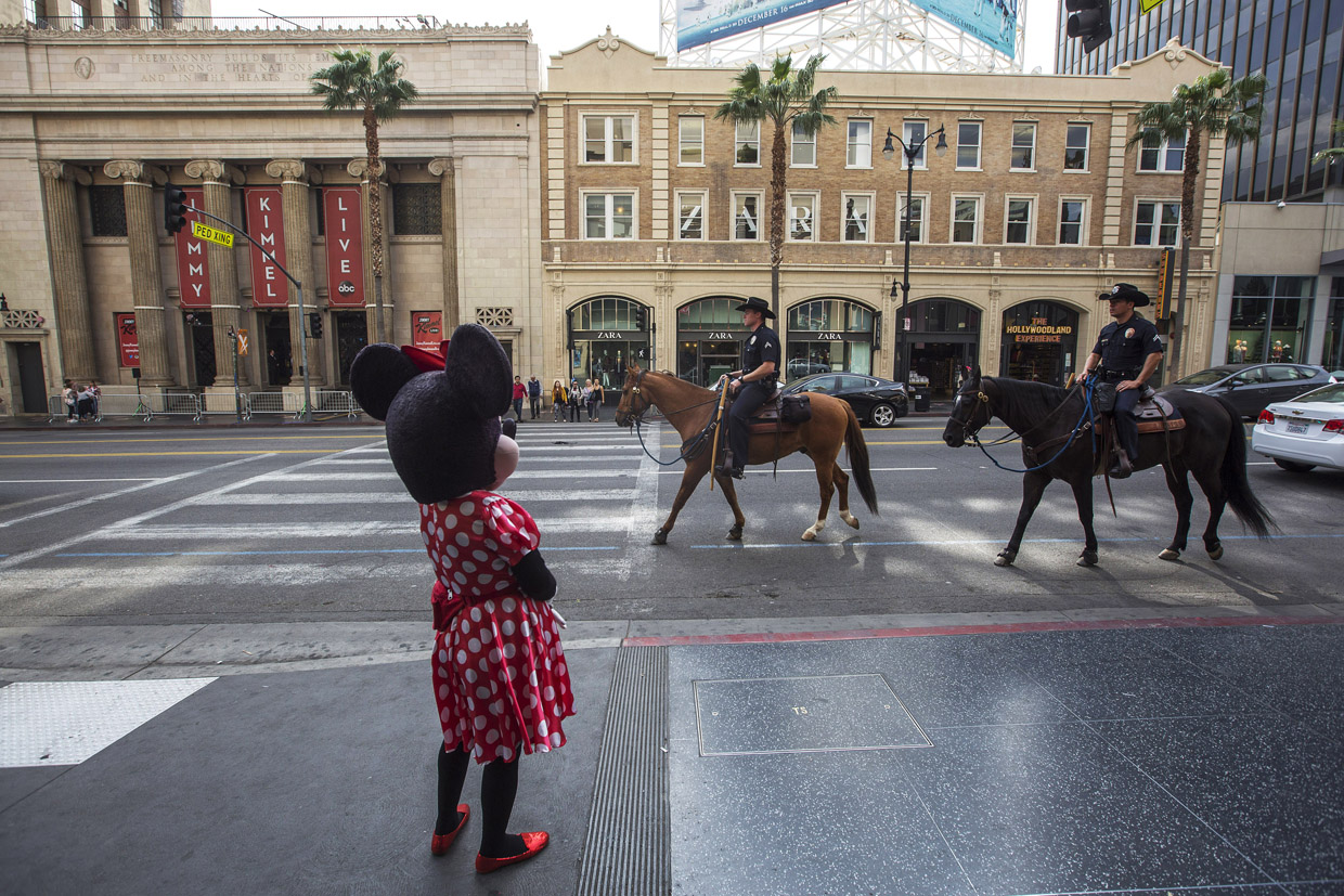 LOS ANGELES, CA - DECEMBER 06: Los Angeles Police Department Mounted Platoon officers ride past a Minnie Mouse character near the Jimmy Kimmel Live studio (L) on Hollywood Boulevard as police and deputies step up security near the Hollywood/Highland Red Line Metro train station and other stops on December 6, 2016 in Los Angeles, California. An increase in security is in response to Federal and Los Angeles officials who say they were alerted by authorities in another country that an imminent and very specific threat has been made against the city's Red Line commuter rail system. (Photo by David McNew/Getty Images)
