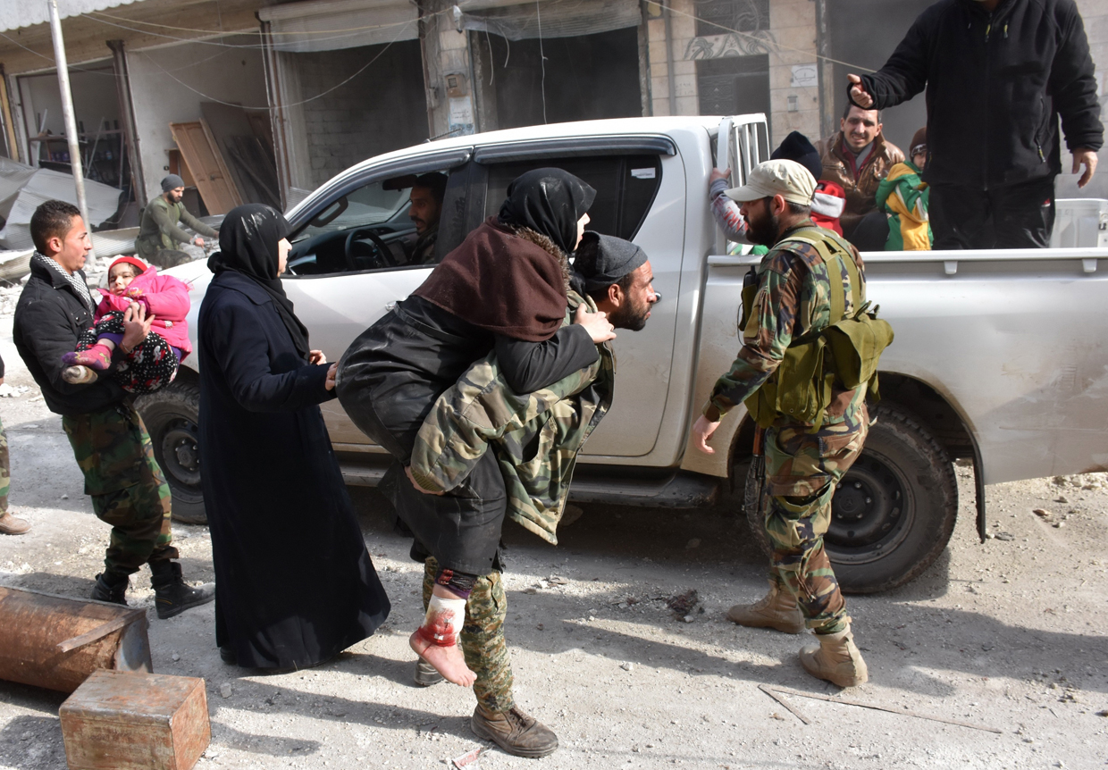 A Syrian pro-government fighter carries a wounded woman who was reportedly shot by rebel sniper fire while fleeing with her family Aleppo's eastern al-Salihin neighbourhood on December 12, 2016 after troops retook the area from rebel fighters. / AFP / GEORGE OURFALIAN (Photo credit should read GEORGE OURFALIAN/AFP/Getty Images)