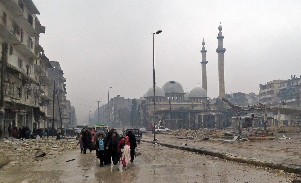 Syrian residents, fleeing violence in the restive Bustan al-Qasr neighbourhood, arrive in Aleppo's Fardos neighbourhood on December 13, 2016, after regime troops retook the area from rebel fighters. Syrian rebels withdrew from six more neighbourhoods in their one-time bastion of east Aleppo in the face of advancing government troops, the Syrian Observatory for Human Rights said. / AFP / STRINGER (Photo credit should read STRINGER/AFP/Getty Images)