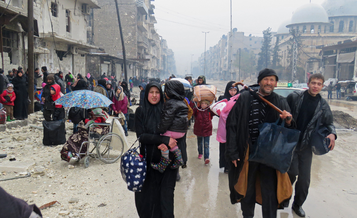 Syrian residents, fleeing violence in the restive Bustan al-Qasr neighbourhood, arrive in Aleppo's Fardos neighbourhood on December 13, 2016, after regime troops retook the area from rebel fighters. Syrian rebels withdrew from six more neighbourhoods in their one-time bastion of east Aleppo in the face of advancing government troops, the Syrian Observatory for Human Rights said. / AFP / STRINGER (Photo credit should read STRINGER/AFP/Getty Images)