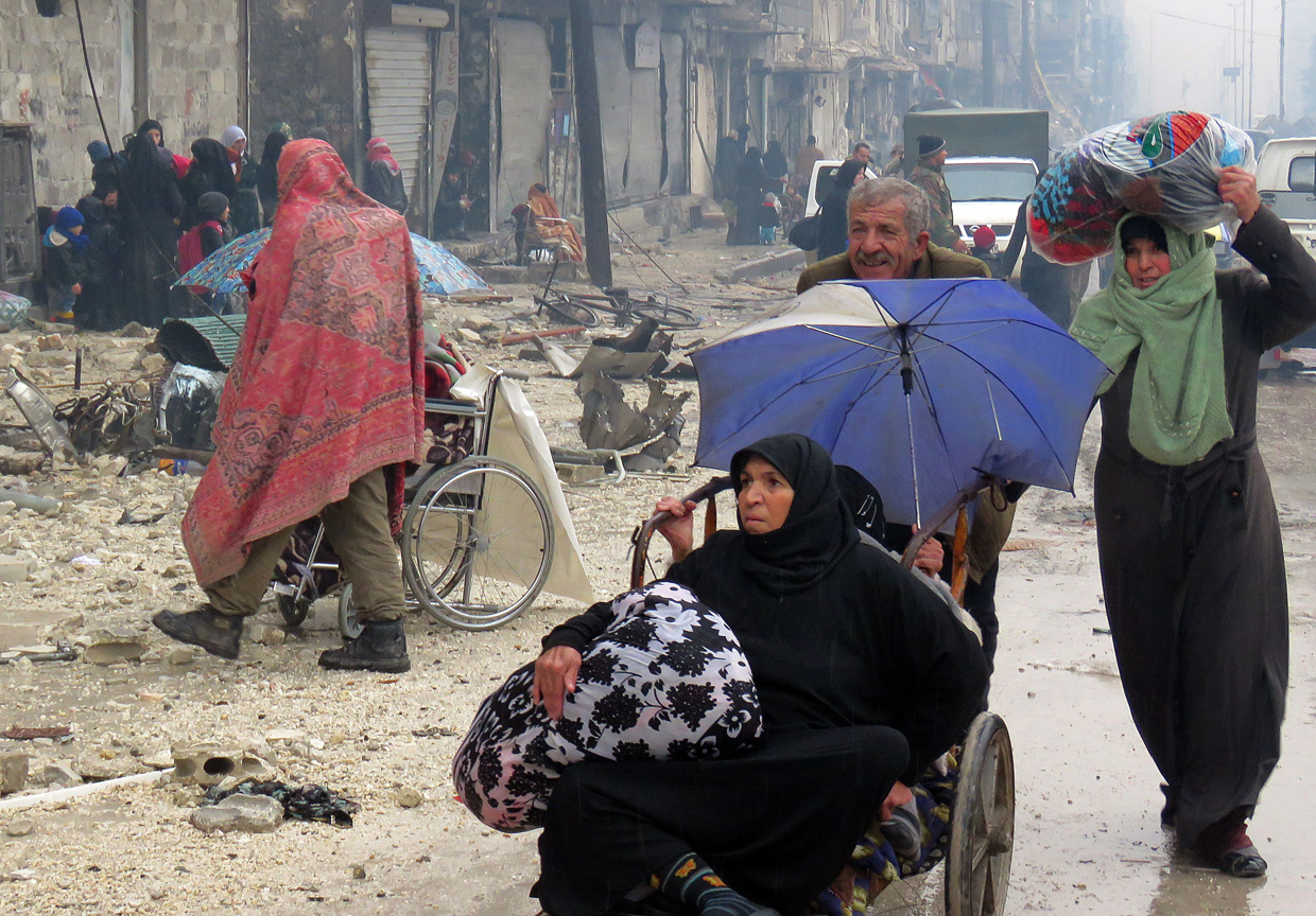 Syrian residents, fleeing violence in the restive Bustan al-Qasr neighbourhood, arrive in Aleppo's Fardos neighbourhood on December 13, 2016, after regime troops retook the area from rebel fighters. Syrian rebels withdrew from six more neighbourhoods in their one-time bastion of east Aleppo in the face of advancing government troops, the Syrian Observatory for Human Rights said. / AFP / STRINGER (Photo credit should read STRINGER/AFP/Getty Images)