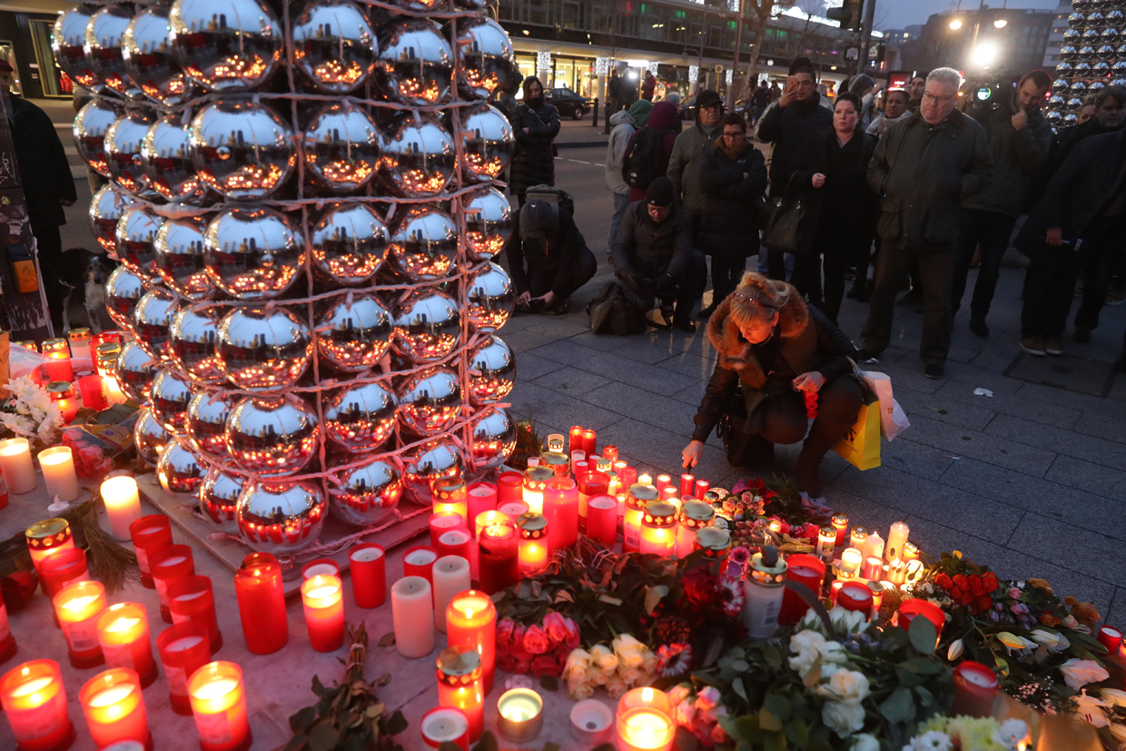 BERLIN, GERMANY - DECEMBER 20: People light candles at the entrance to the Christmas market close to where the lorry ploughed through it yesterday on December 20, 2016 in Berlin, Germany. So far 12 people are confirmed dead and 45 injured. Authorities have confirmed they believe the incident was an attack and have arrested a Pakistani man who they believe was the driver of the truck and who had fled immediately after the attack. Among the dead are a Polish man who was found on the passenger seat of the truck. Police are investigating the possibility that the truck, which belongs to a Polish trucking company, was stolen yesterday morning. (Photo by Sean Gallup/Getty Images)