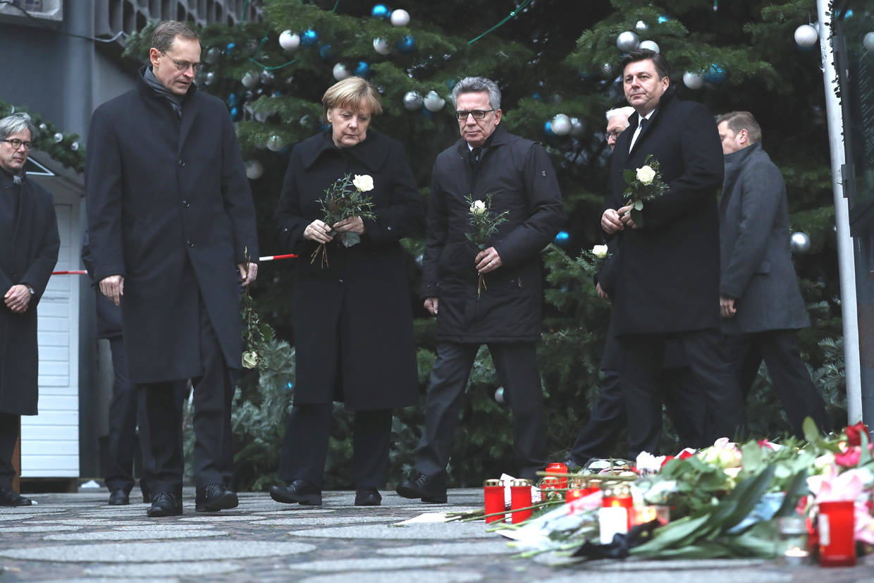 BERLIN, GERMANY - DECEMBER 20: (L-R) Mayor of Berlin Michael Mueller, German Chancellor Angela Merkel, German Interior Minister Thomas de Maiziere and Berlin city Interior Minister Andreas Geisel arrive to lay flowers near where yesterday a lorry ploughed through a Christmas market on December 20, 2016 in Berlin, Germany. So far 12 people are confirmed dead and 45 injured. Authorities have confirmed they believe the incident was an attack and have arrested a Pakistani man who they believe was the driver of the truck and who had fled immediately after the attack. Among the dead are a Polish man who was found on the passenger seat of the truck. Police are investigating the possibility that the truck, which belongs to a Polish trucking company, was stolen yesterday morning. (Photo by Sean Gallup/Getty Images)
