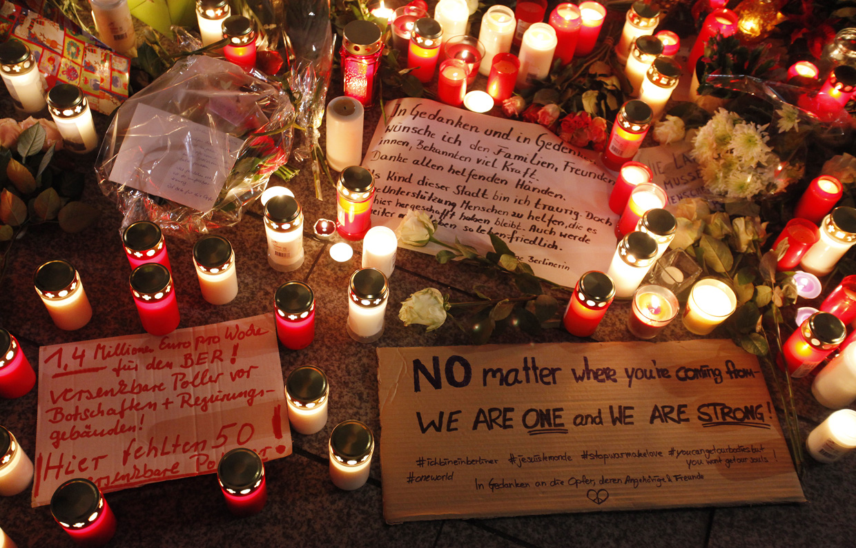 BERLIN, GERMANY - DECEMBER 20: Signs lay on the ground as people leave flowers and candles at the area after a lorry truck ploughed through a Christmas market on December 20, 2016 in Berlin, Germany. So far 12 people are confirmed dead and 45 injured. Authorities have confirmed they believe the incident was an attack and have arrested a Pakistani man who they believe was the driver of the truck and who had fled immediately after the attack. Among the dead are a Polish man who was found on the passenger seat of the truck. Police are investigating the possibility that the truck, which belongs to a Polish trucking company, was stolen yesterday morning. (Photo by Michele Tantussi/Getty Images)