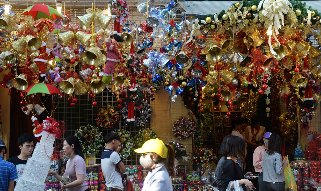 People walk past a shop selling Christmas items in downtown Hanoi on December 21, 2016. / AFP / HOANG DINH NAM (Photo credit should read HOANG DINH NAM/AFP/Getty Images)