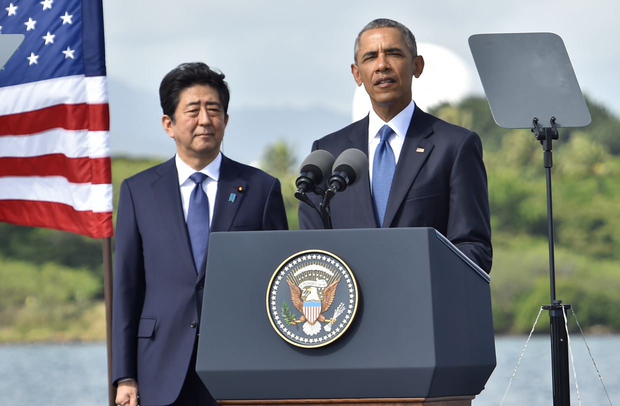 US President Barack Obama (C) speaks as Japanese Prime Minister Shinzo Abe listens at Kilo Pier overlooking the USS Arizona Memorial on December 27, 2016 at Pearl Harbor in Honolulu, Hawaii. Abe and Obama made a joint pilgrimage to the site of the Pearl Harbor attack on Tuesday to celebrate "the power of reconciliation. "The Japanese attack on an unsuspecting US fleet moored at Pearl Harbor turned the Pacific into a cauldron of conflict -- more than 2,400 were killed and a reluctant America was drawn into World War II. / AFP / Nicholas Kamm (Photo credit should read NICHOLAS KAMM/AFP/Getty Images)