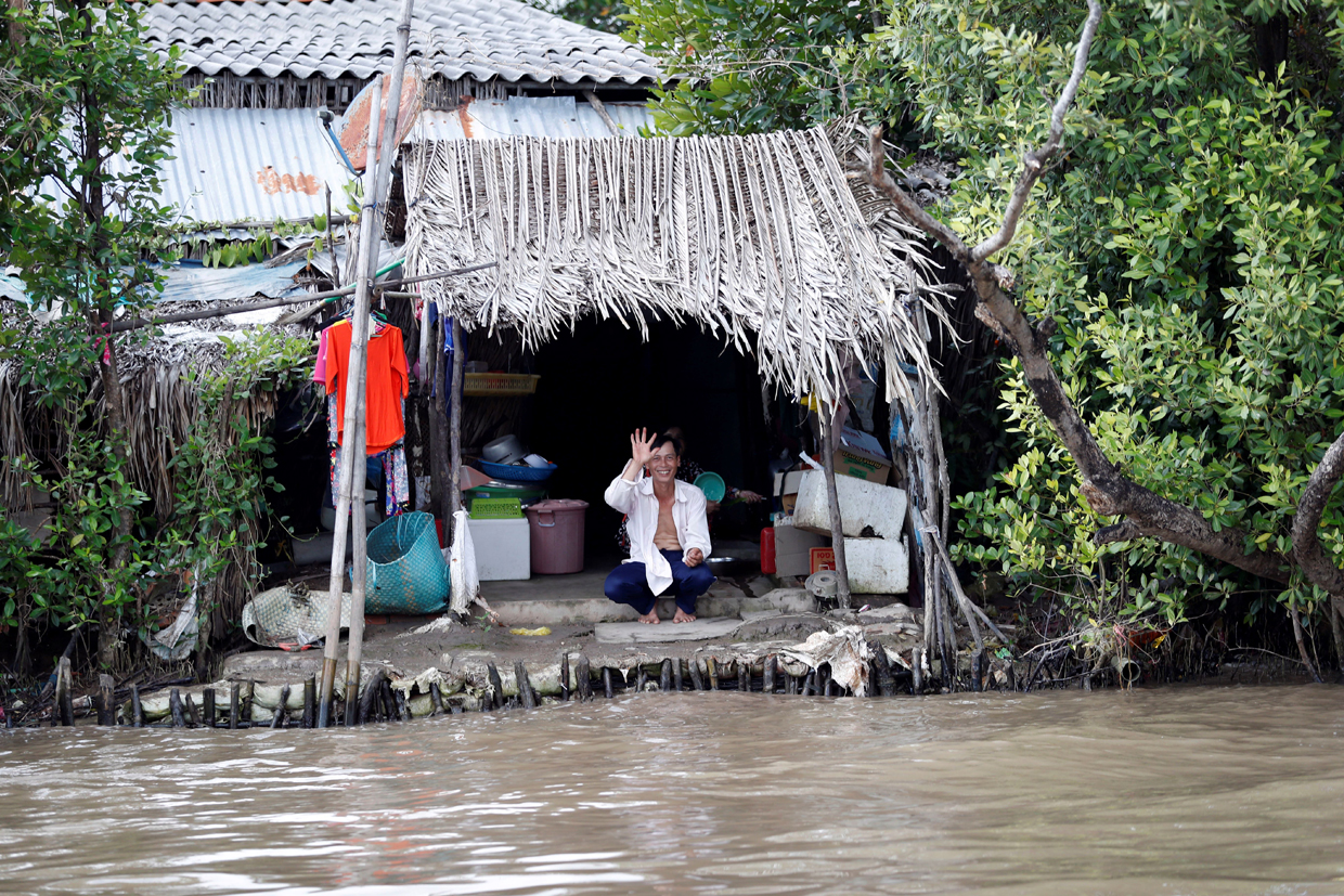 A man waves as the boat with US Secretary of State John Kerry aboard travels past him in the Mekong River Delta on January 14, 2017. Kerry is in Vietnam, his fourth and final trip to the communist nation where he served during the war. / AFP / POOL / Alex Brandon (Photo credit should read ALEX BRANDON/AFP/Getty Images)