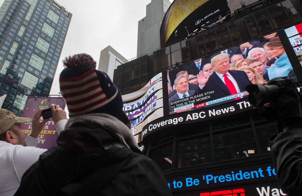 People watch the inauguration of Donald Trump on a screen in Times Square on January 20, 2017 in New York. Barack Obama and Donald Trump arrived at the US Capitol on Friday where the president-elect was sworn in as the United States' 45th head of state. / AFP / Bryan R. Smith (Photo credit should read BRYAN R. SMITH/AFP/Getty Images)
