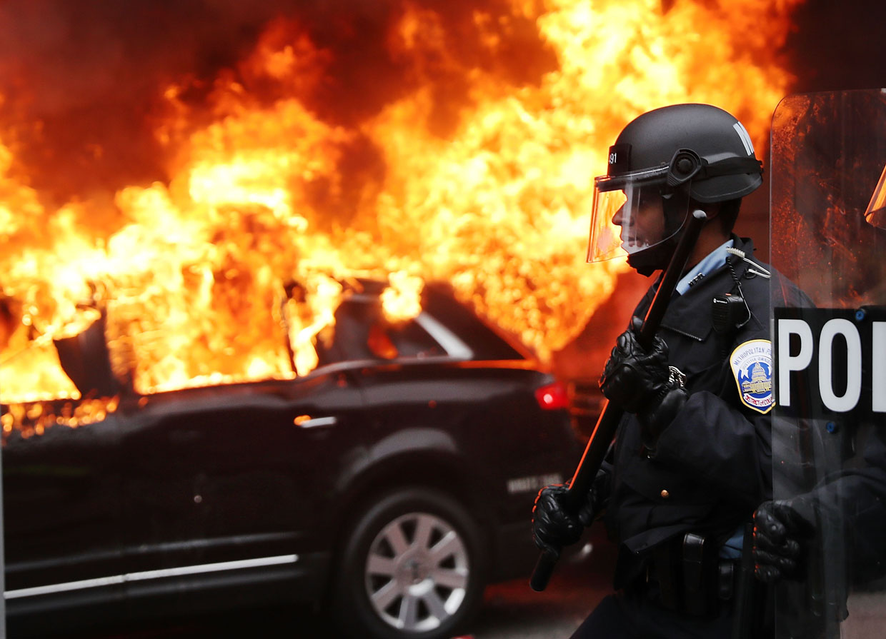 WASHINGTON, DC - JANUARY 20: Police and demonstrators clash in downtown Washington after a limo was set on fire following the inauguration of President Donald Trump on January 20, 2017 in Washington, DC. Washington and the entire world have watched the transfer of the United States presidency from Barack Obama to Donald Trump, the 45th president. (Photo by Spencer Platt/Getty Images)