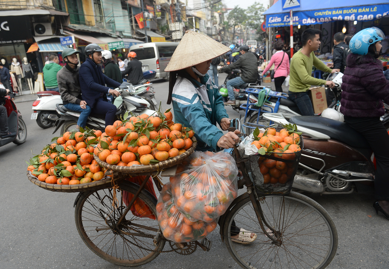 A street vendor hawks oranges along a street in downtown Hanoi on January 23, 2017, as Vietnamese prepare to celebrate the Lunar New Year or Tet later this week. Known locally as Tet, the celebration of the Lunar New Year is Vietnam's most important holiday and triggers a surge in consumption and travel ahead of an extended nationwide shutdown. / AFP / HOANG DINH NAM (Photo credit should read HOANG DINH NAM/AFP/Getty Images)