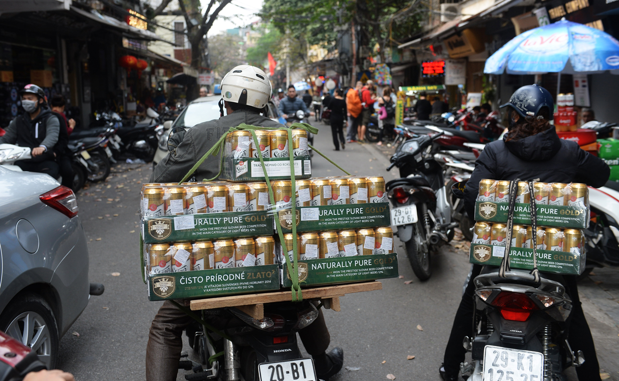 A delivery man (L) leaves a drink shop with boxes of imported beer in downtown Hanoi on January 23, 2017, as Vietnamese prepare to celebrate the Lunar New Year or Tet later this week. Known locally as Tet, the celebration of the Lunar New Year is Vietnam's most important holiday and triggers a surge in consumption and travel ahead of an extended nationwide shutdown. / AFP / HOANG DINH NAM (Photo credit should read HOANG DINH NAM/AFP/Getty Images)