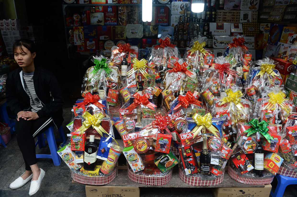 A shopkeeper sits next to boxes of gifts for the Lunar New Year, or Tet, at a shop in downtown Hanoi on January 23, 2017, as Vietnamese prepare to celebrate the Lunar New Year or Tet later this week. Known locally as Tet, the celebration of the Lunar New Year is Vietnam's most important holiday and triggers a surge in consumption and travel ahead of an extended nationwide shutdown. / AFP / HOANG DINH NAM (Photo credit should read HOANG DINH NAM/AFP/Getty Images)