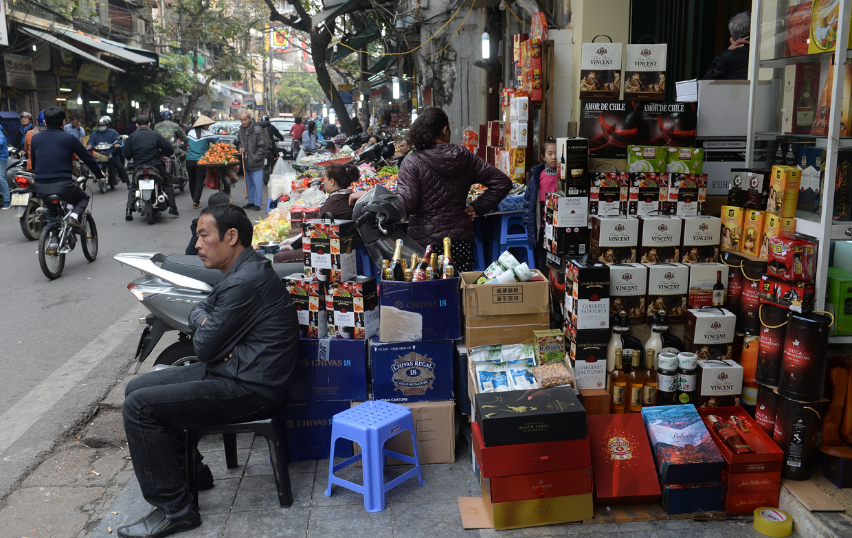 A man sits in front of his stand offering chocolates, sweets, drinks and wine for in downtown Hanoi on January 23, 2017, as Vietnamese prepare to celebrate the Lunar New Year or Tet later this week. Known locally as Tet, the celebration of the Lunar New Year is Vietnam's most important holiday and triggers a surge in consumption and travel ahead of an extended nationwide shutdown. / AFP / HOANG DINH NAM (Photo credit should read HOANG DINH NAM/AFP/Getty Images)