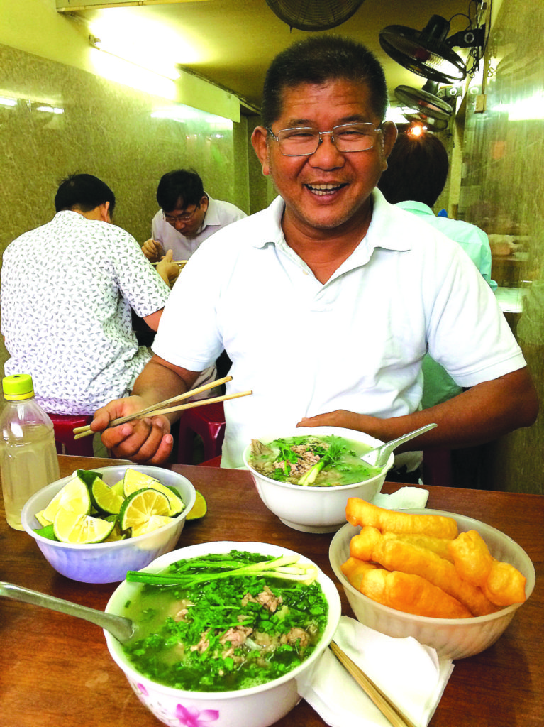 Nụ cười mãn nguyện của Ðỗ Dzũng trước khi được nếm thử món phở Hà Nội. (Hình: Khôi Nguyên/Người Việt)