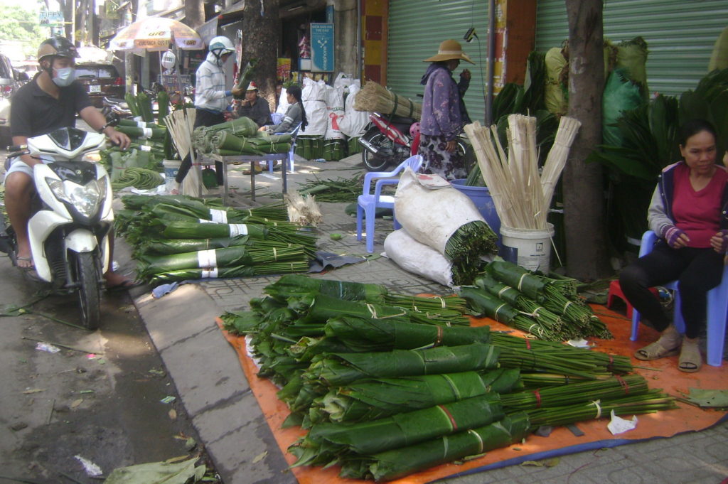 Lá dong gói bánh được bày bán trên hè phố Sài Gòn. (Hình: Văn Lang/Người Việt)