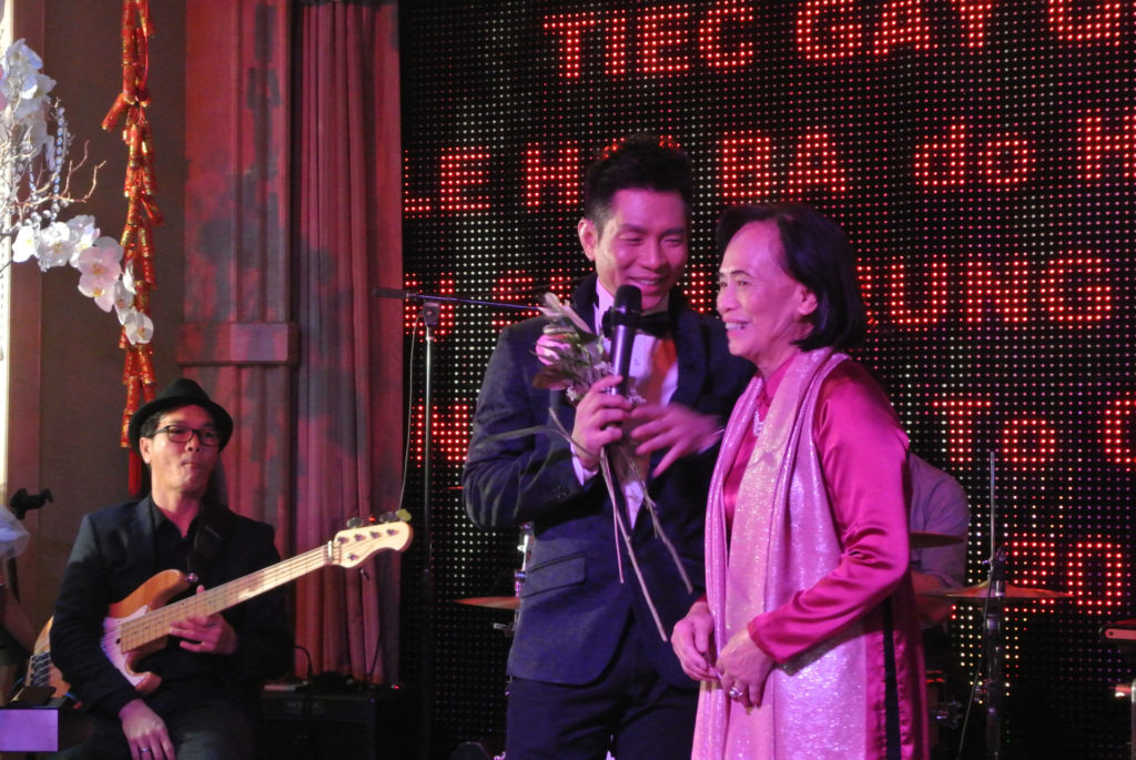 Giáo Sư Trịnh Thúy Nga tặng hoa ca sĩ Trần Thái Hòa. (Hình: Minh Phú/Người Việt)
