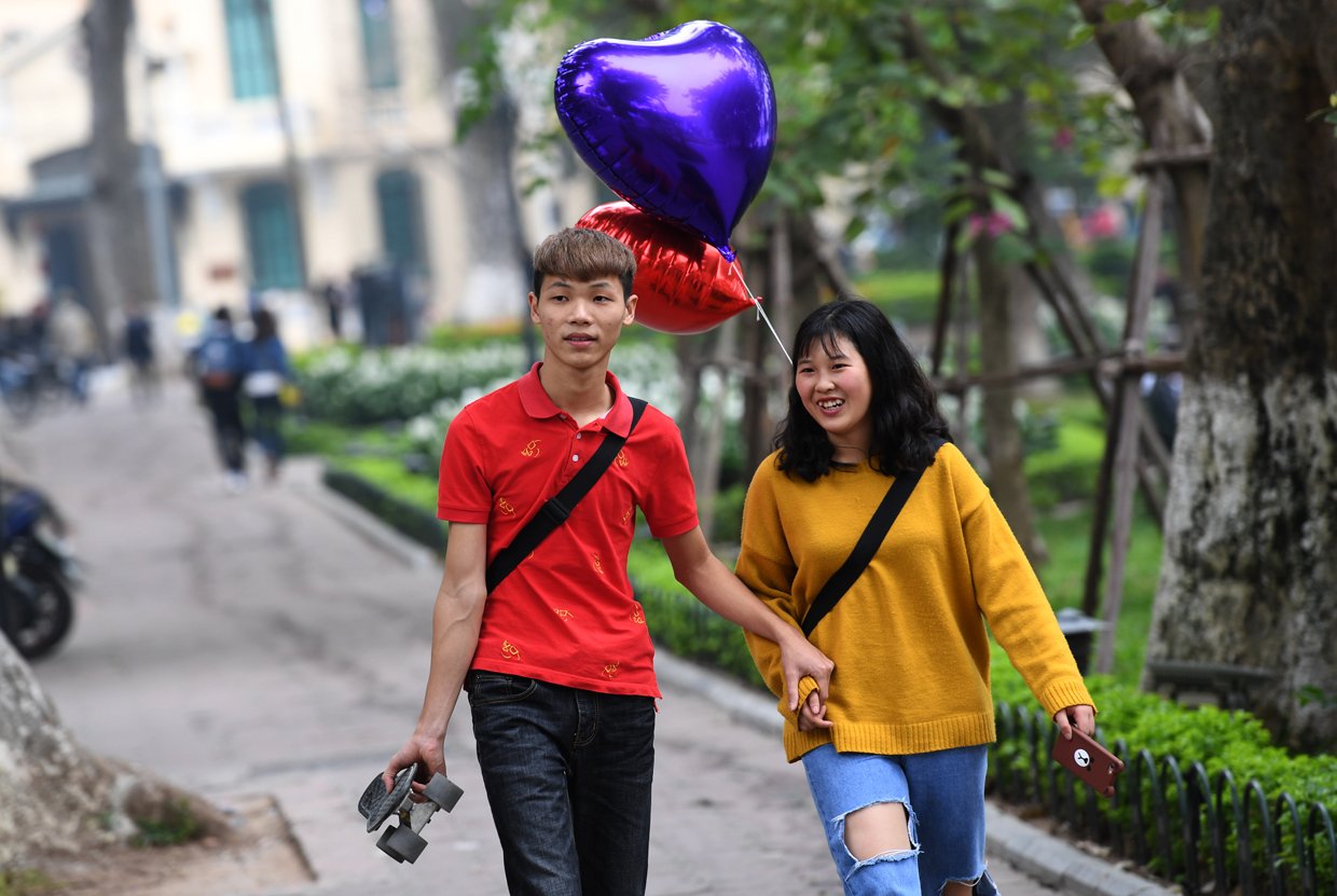A couple walks with heart-shaped balloons at a public park on Valentine's Day in Hanoi on February 14, 2017. / AFP / HOANG DINH NAM (Photo credit should read HOANG DINH NAM/AFP/Getty Images)