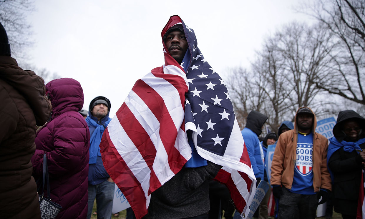 WASHINGTON, DC - FEBRUARY 16: Fast food chain worker Tino Akata of Silver Spring, Maryland, wraps a U.S. flag around himself during a rally "to fight-back against the Republican war on the working class" February 16, 2017 at Upper Senate Park on Capitol Hill in Washington, DC. Activists held a rally to celebrate Andrew Puzder's decision to withdraw from consideration to be secretary of labor and "to hold [President] Trump accountable to the working class." (Photo by Alex Wong/Getty Images)