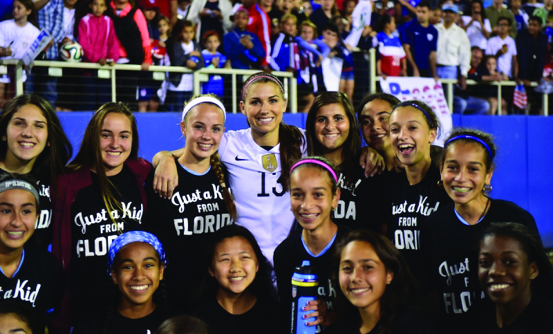 Nữ tiền đạo Alex Morgan số 13 (giữa) cùng các nữ cổ động viên. (Hình: USSoccer.com)