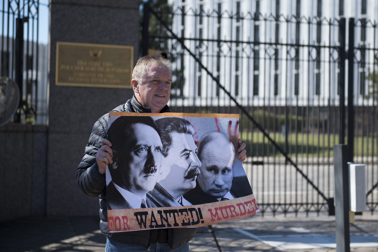 A protester holds a sign outside the Embassy of Russia on March 4, 2017, in Washington, DC. / AFP PHOTO / MOLLY RILEY (Photo credit should read MOLLY RILEY/AFP/Getty Images)