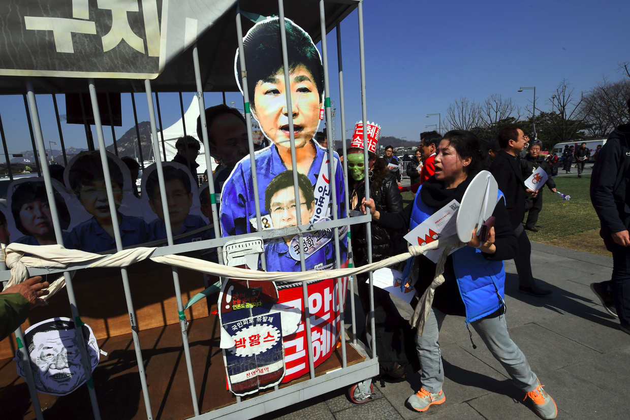 TOPSHOT - Anti-government activists carry a mock prison containing a board-cut of South Korea's President Park Geun-Hye after the announcement of the Constitutional Court's decision to uphold the impeachment of Park in Seoul on March 10, 2017. South Korean President Park Geun-Hye was fired by the country's top court on March 10, as it upheld her impeachment by parliament over a wide-ranging corruption scandal. / AFP PHOTO / JUNG Yeon-Je (Photo credit should read JUNG YEON-JE/AFP/Getty Images)