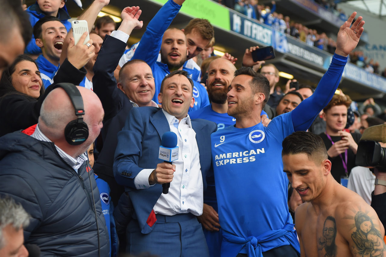 Chủ tịch đội bóng Brighton, Tony Bloom (cầm microphone) vui mừng với các cầu thủ sau khi trận đấu giải Championship giữa Brington và Wigan Athletic trên sân Amex Stadium, ngày 17 Tháng Tư kết thúc với kết quả Brighton đá bại Wigan 2-1 để chính thức được thăng hạng Premier League vào mùa tới. (Hình: Getty Images)