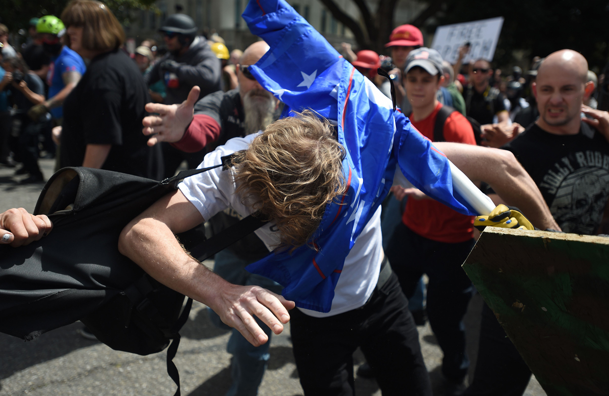 A man gets hit over the head with a Trump flag as multiple fights break out between Trump supporters and anti-Trump protesters in Berkeley, California on April 15, 2017. Hundreds of people with opposing opinions on President Donald Trump threw stones, lit fires, tossed explosives and tear gas and attacked each other with makeshift weapons as police stood by. / AFP PHOTO / Josh Edelson (Photo credit should read JOSH EDELSON/AFP/Getty Images)