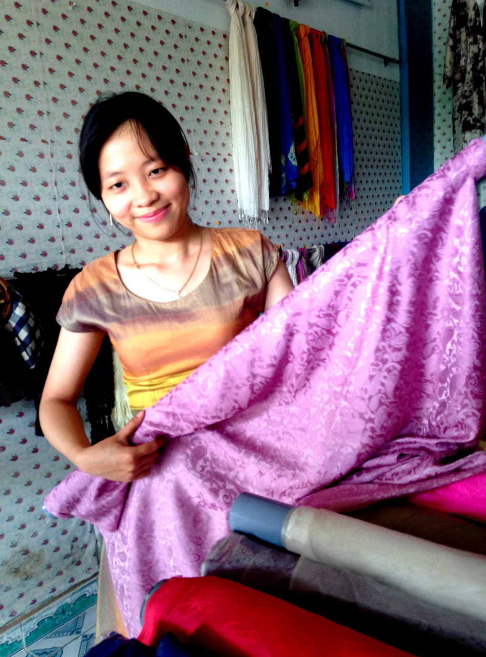 Cô Trần Thị Yến, chủ cơ sở lụa, bên khúc Mã Châu nhuộm màu từ chất liệu thiên nhiên. (Hình: Trần Tiến Dũng/Người Việt)