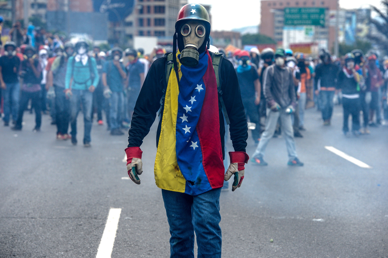 TOPSHOT - Opposition activists protest against President Nicolas Maduro, in Caracas on May 8, 2017. Venezuela's opposition mobilized Monday in fresh street protests against President Nicolas Maduro's efforts to reform the constitution in a deadly political crisis. Supporters of the opposition Democratic Unity Roundtable (MUD) gathered in eastern Caracas to march to the education ministry under the slogan "No to the dictatorship." / AFP PHOTO / FEDERICO PARRA (Photo credit should read FEDERICO PARRA/AFP/Getty Images)