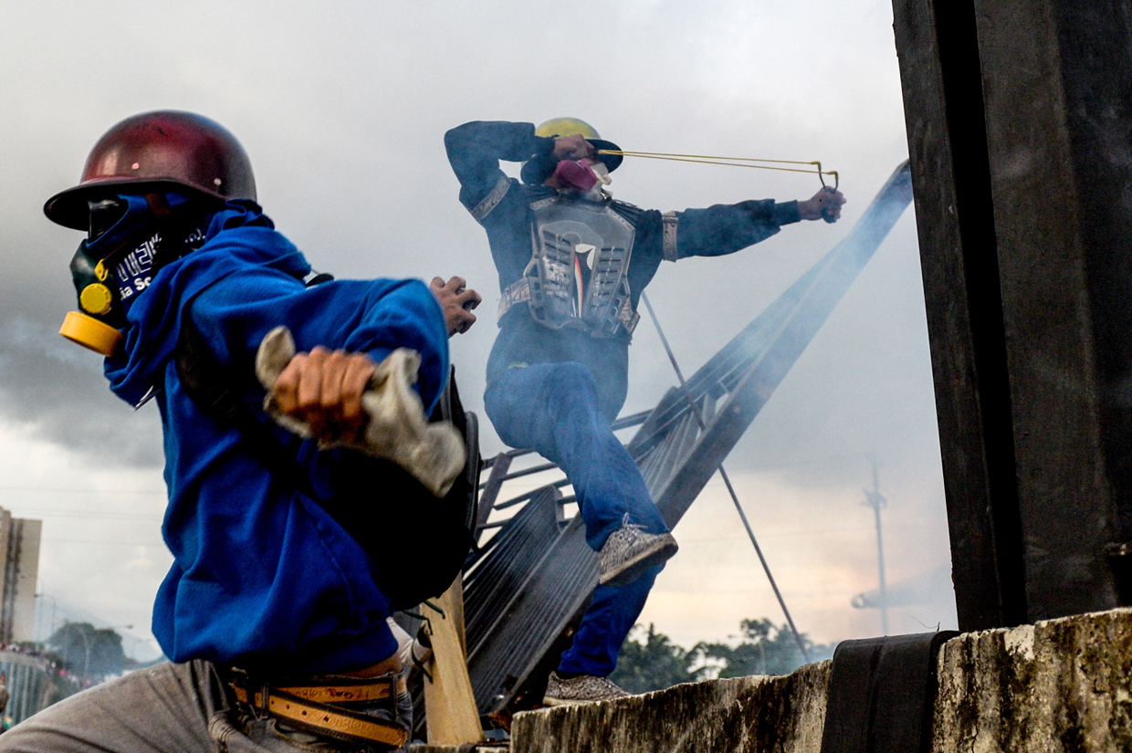 TOPSHOT - Opposition activists and riot police clash during a protest against President Nicolas Maduro, in Caracas on May 8, 2017. Venezuela's opposition mobilized Monday in fresh street protests against President Nicolas Maduro's efforts to reform the constitution in a deadly political crisis. Supporters of the opposition Democratic Unity Roundtable (MUD) gathered in eastern Caracas to march to the education ministry under the slogan "No to the dictatorship." / AFP PHOTO / FEDERICO PARRA (Photo credit should read FEDERICO PARRA/AFP/Getty Images)