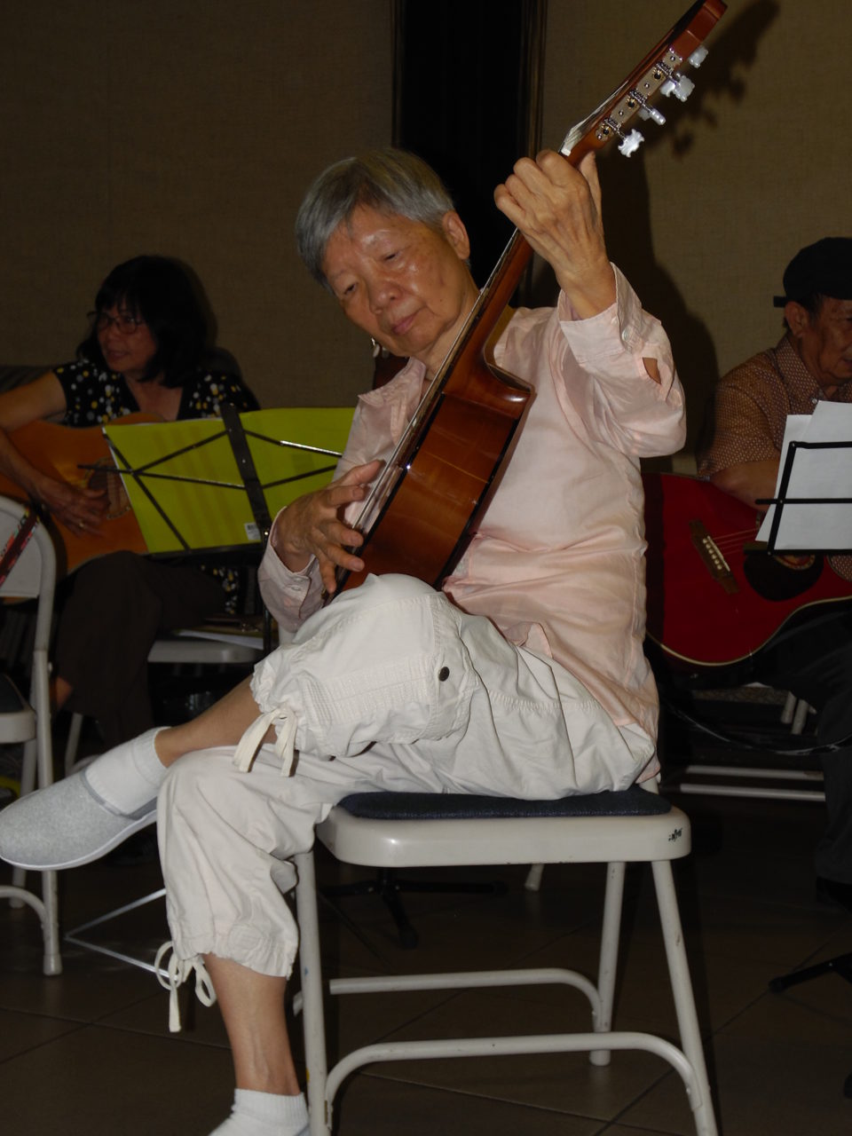 Bà Nguyễn Kim Anh, 76 tuổi, chăm chú học đàn. (Hình: Linh Nguyễn/Người Việt)