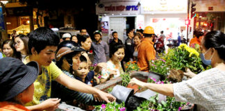 Nhiều người chen nhau chờ lấy hoa bỏ. (Hình: Báo Thanh Niên)